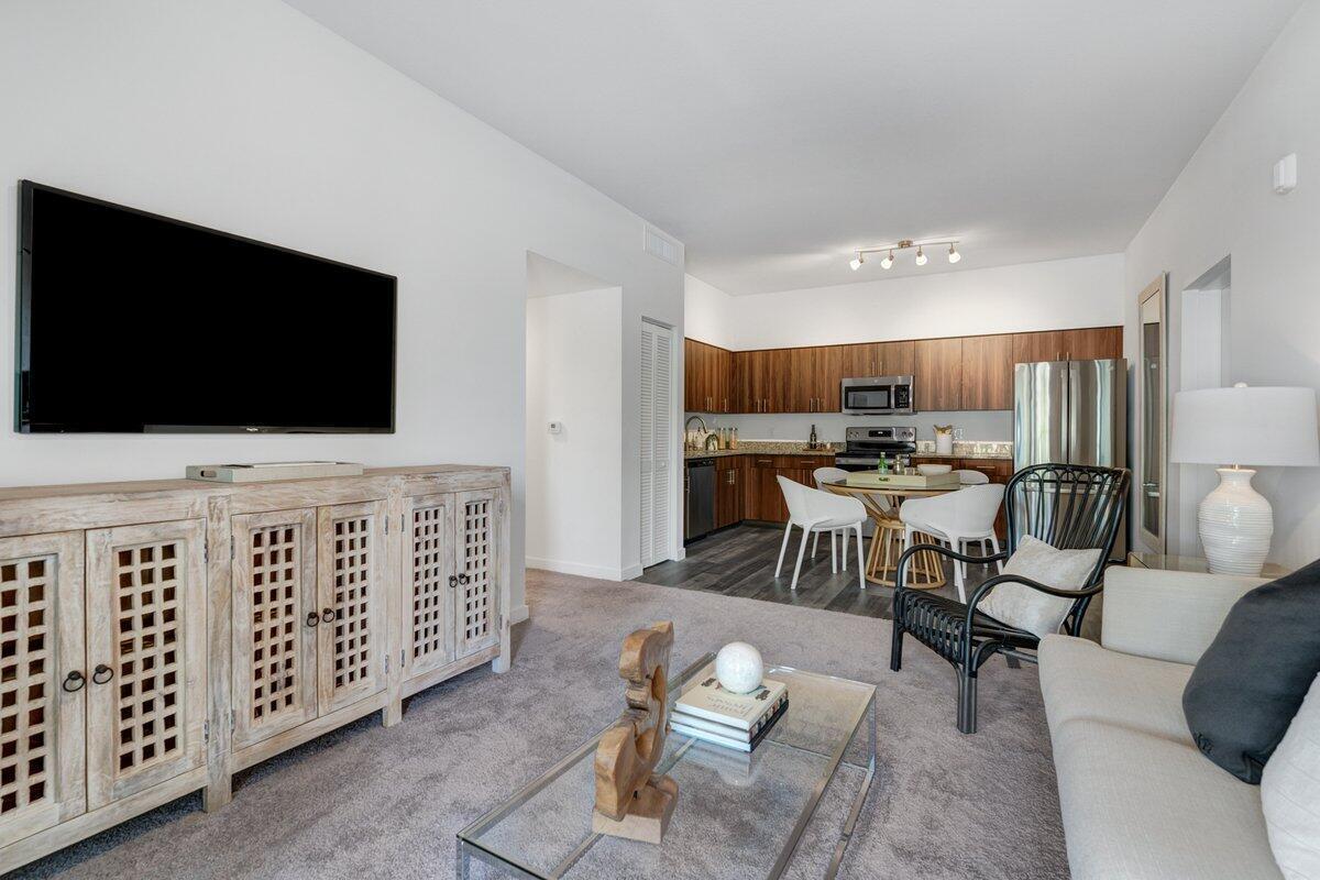 A living room with a television, wooden cabinet, and an adjacent kitchen with dining area — 4290 Lakewood Road Unit 107, FL 33461, FL