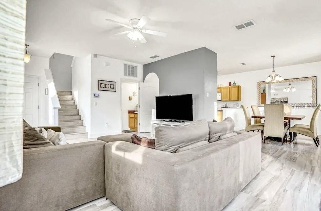 A living room with a gray sectional sofa, a television, and stairs leading to a loft — 540 SANDY RIDGE DRIVE, DAVENPORT, FL