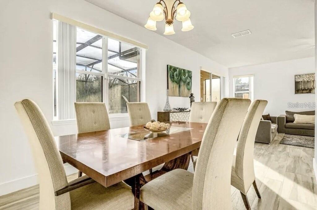 A dining room with a wooden table, upholstered chairs, and a chandelier near a window — 540 SANDY RIDGE DRIVE, DAVENPORT, FL