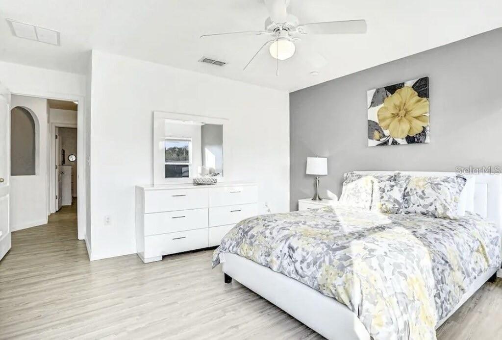 A bedroom features light wood flooring, a white dresser with a mirror, and a gray accent wall — 540 SANDY RIDGE DRIVE, DAVENPORT, FL