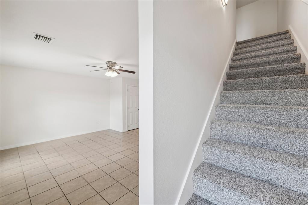 A tiled room with a ceiling fan sits beside a carpeted staircase leading upstairs — 210 MAJORS LANE UNIT B, KISSIMMEE, FL