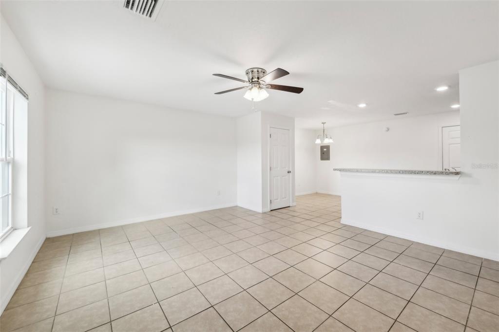 An open-concept living area features light-colored tile flooring, white walls, and a ceiling fan — 210 MAJORS LANE UNIT B, KISSIMMEE, FL