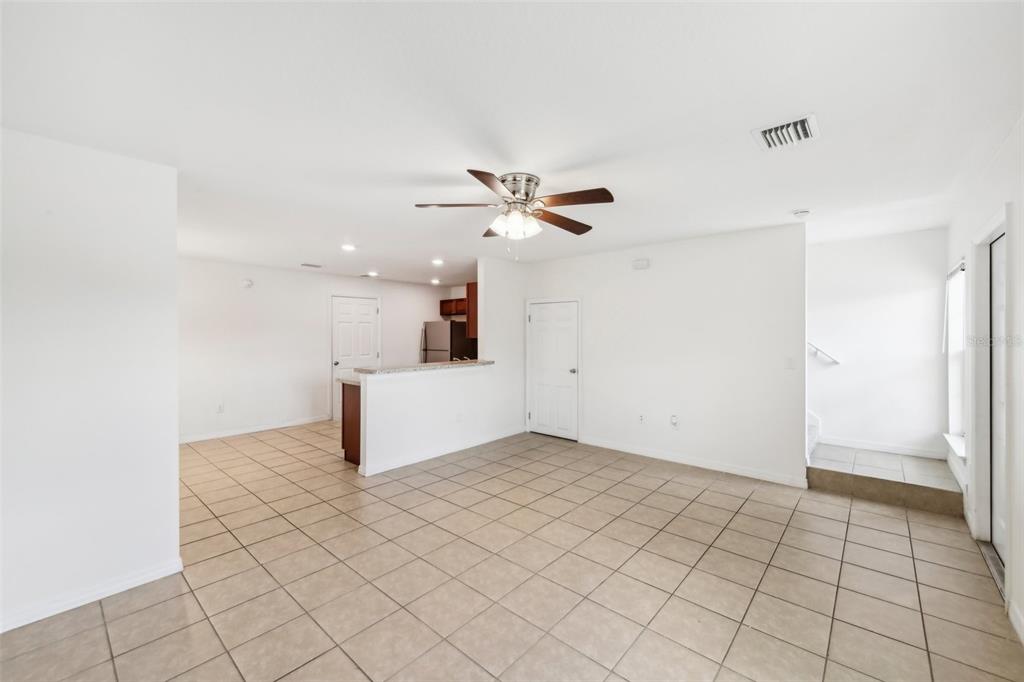 An open-concept living area features light-colored tile flooring, a ceiling fan, and a kitchen pass-through — 210 MAJORS LANE UNIT B, KISSIMMEE, FL