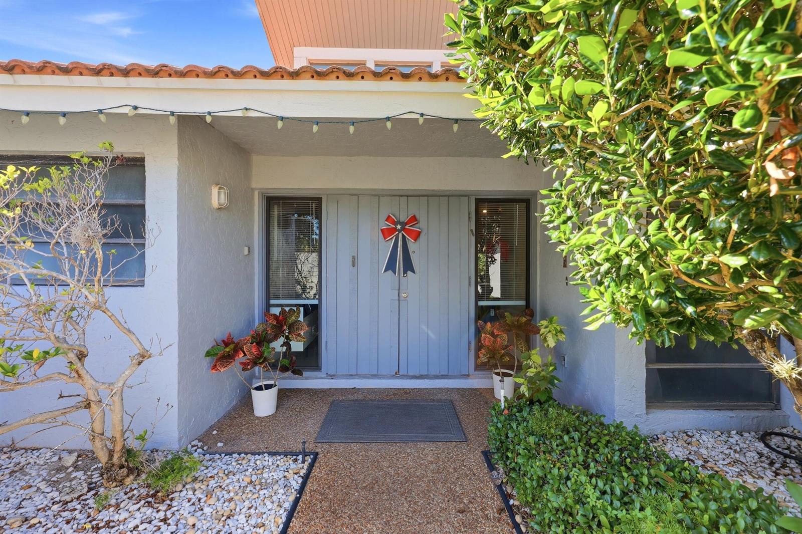 A light blue double front door with a patriotic bow sits under a covered entryway — 5141 NW 3rd Terrace, Boca Raton FL 33487, BOCA RATON, FL