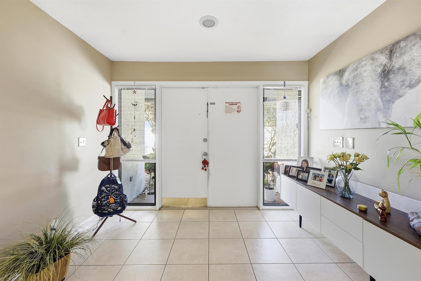 A bright entryway features tiled floors, a white double door, and a modern console table — 5141 NW 3rd Terrace, Boca Raton FL 33487, BOCA RATON, FL