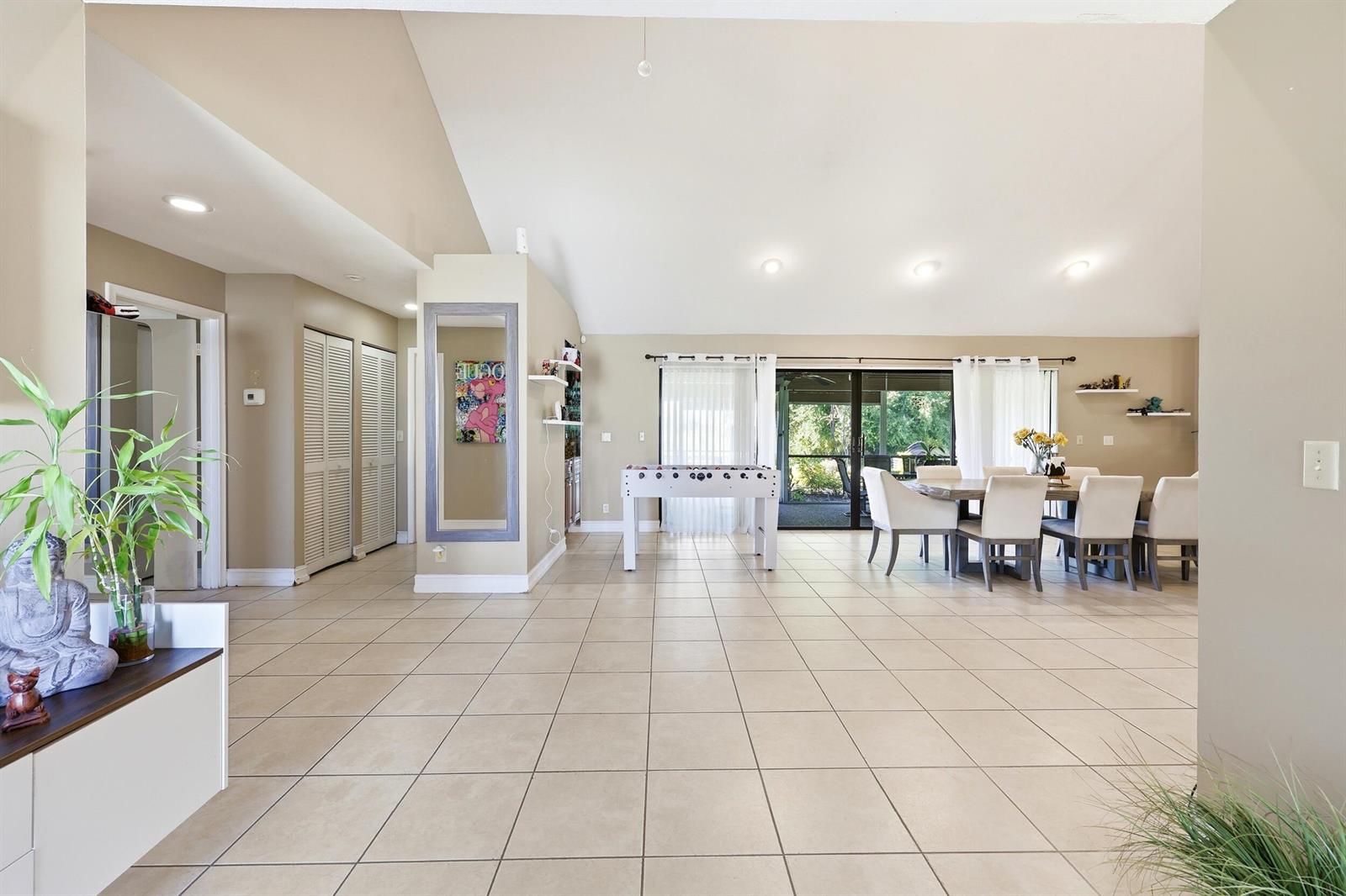 A spacious, open-concept living area features light tile flooring, a foosball table, and dining furniture — 5141 NW 3rd Terrace, Boca Raton FL 33487, BOCA RATON, FL