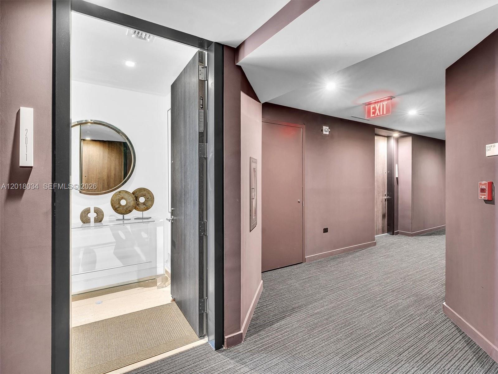 An open apartment door reveals a foyer with a mirror and console table near a hallway — 88 SW 7th St, Miami FL 33130, MIAMI, FL