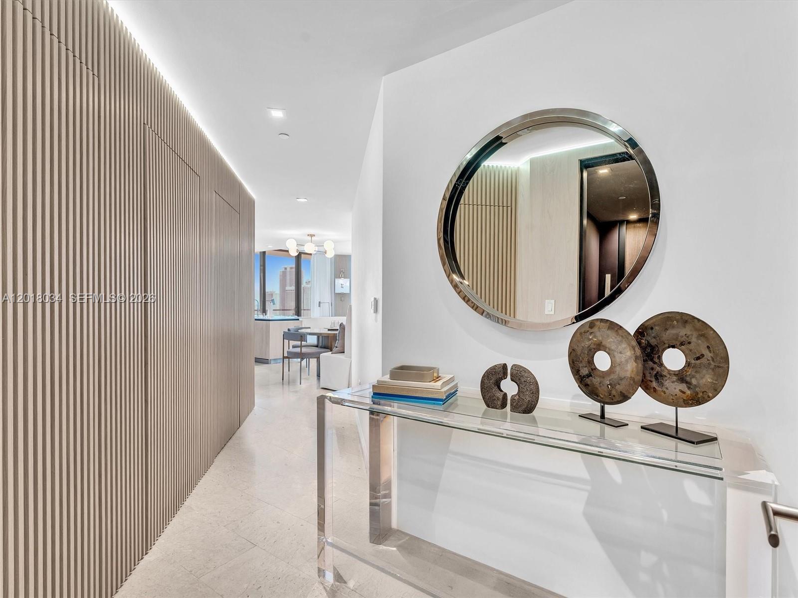 A hallway with slatted wood walls leads to a dining area featuring a glass console table — 88 SW 7th St, Miami FL 33130, MIAMI, FL