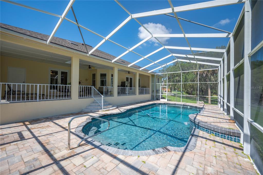 A screened-in patio features a swimming pool with a spa and a paved deck — 6617 POLEY CREEK DRIVE W, LAKELAND, FL