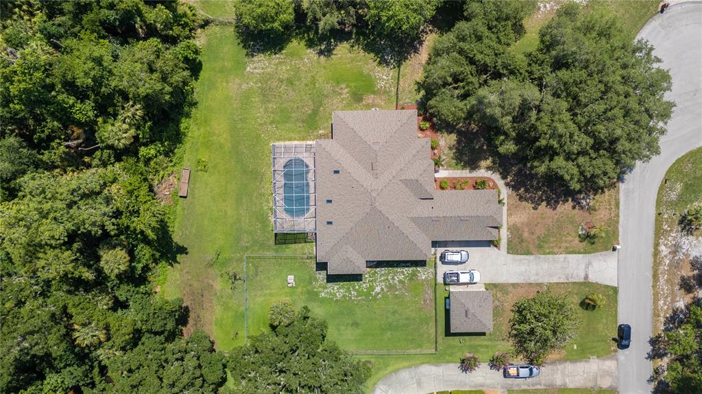 An aerial view shows a house with a screened pool, a driveway, and surrounding trees — 6617 POLEY CREEK DRIVE W, LAKELAND, FL