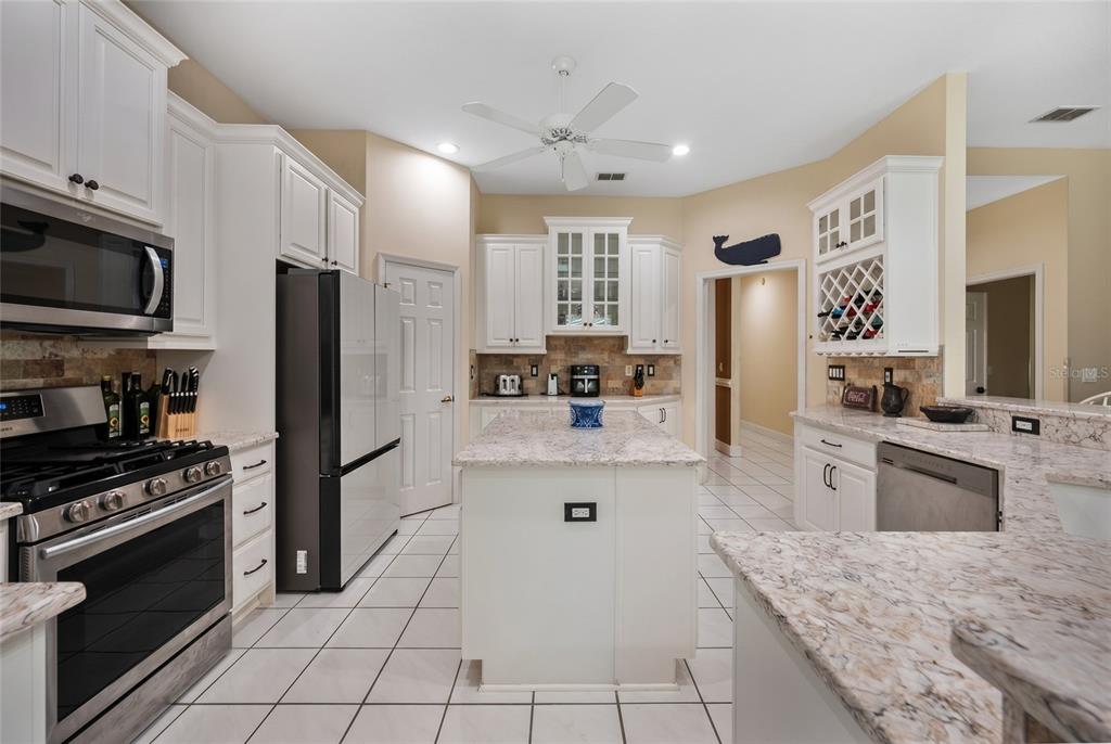 A kitchen features white cabinetry, granite countertops, a center island, and stainless steel appliances — 6617 POLEY CREEK DRIVE W, LAKELAND, FL