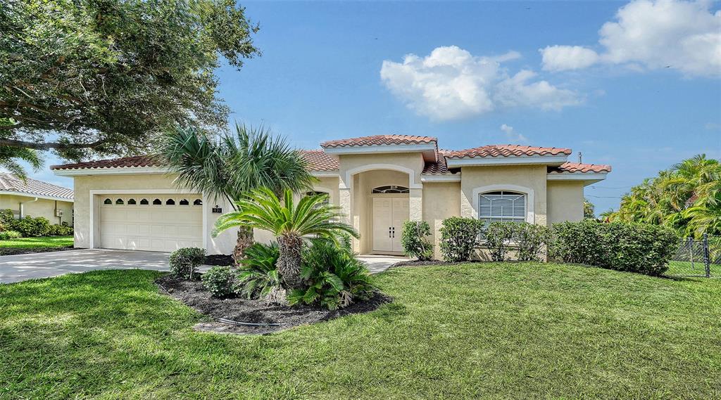 A single-story house with a beige stucco exterior, a tile roof, and a two-car garage — 439 E ROSSETTI DRIVE, NOKOMIS, FL