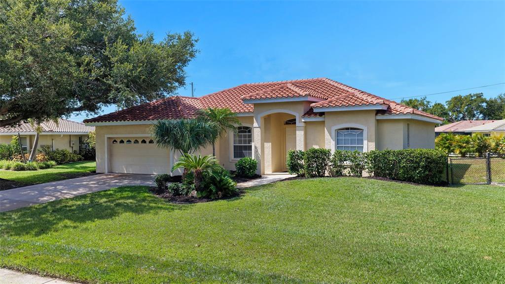 A single-story house with a tile roof, beige stucco exterior, and a two-car garage — 439 E ROSSETTI DRIVE, NOKOMIS, FL