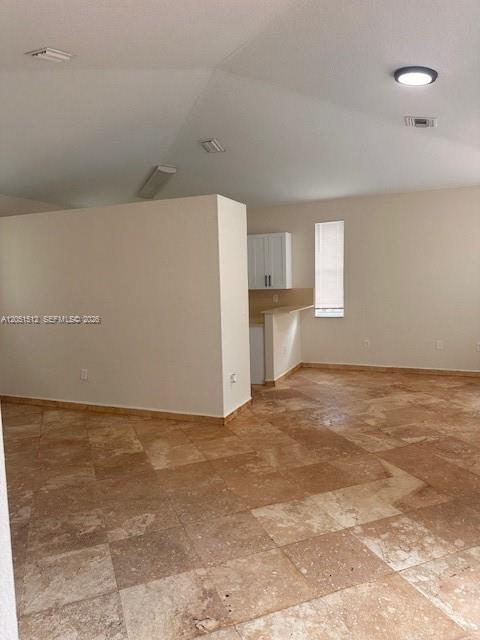 An open-concept room features vaulted ceilings, light-colored walls, and large tan stone floor tiles — 21733 Ingraham Ave Rd # 21733, Cutler Bay FL 33190, CUTLER BAY, FL