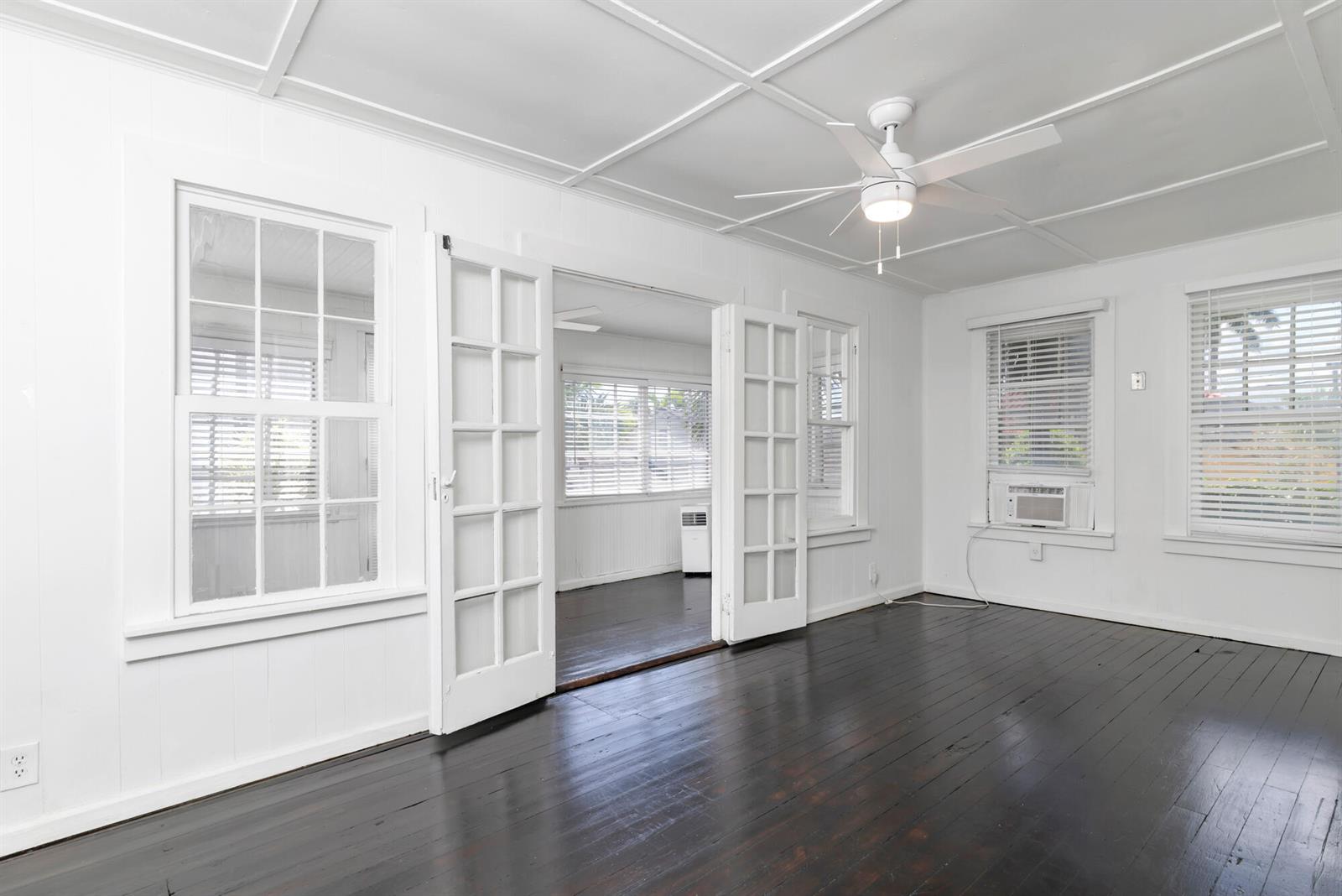 A bright room with dark wood floors, white walls, a ceiling fan, and French doors — 204 Conniston Road, West Palm Beach FL 33405, WEST PALM BEACH, FL