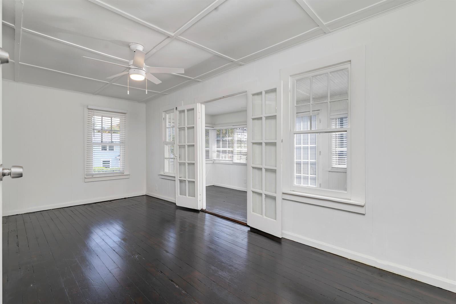 An empty room with dark wood floors, white walls, a ceiling fan, and French doors — 204 Conniston Road, West Palm Beach FL 33405, WEST PALM BEACH, FL