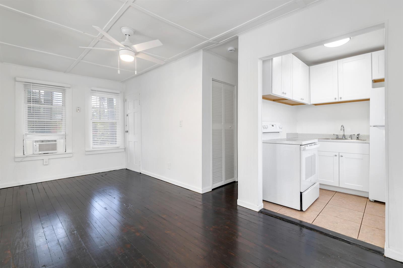 A living area with dark wood floors and a ceiling fan leads into a kitchen — 204 Conniston Road, West Palm Beach FL 33405, WEST PALM BEACH, FL