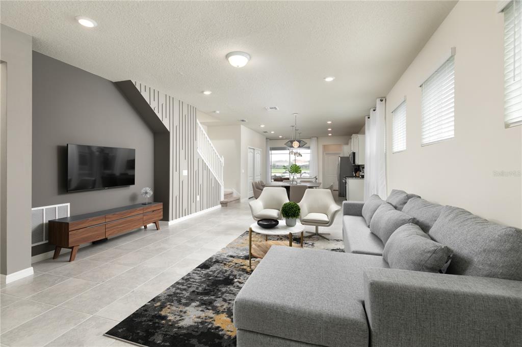 A modern living room features a grey accent wall, tile flooring, and a sectional sofa — 7376 OAKMOSS LOOP, DAVENPORT, FL