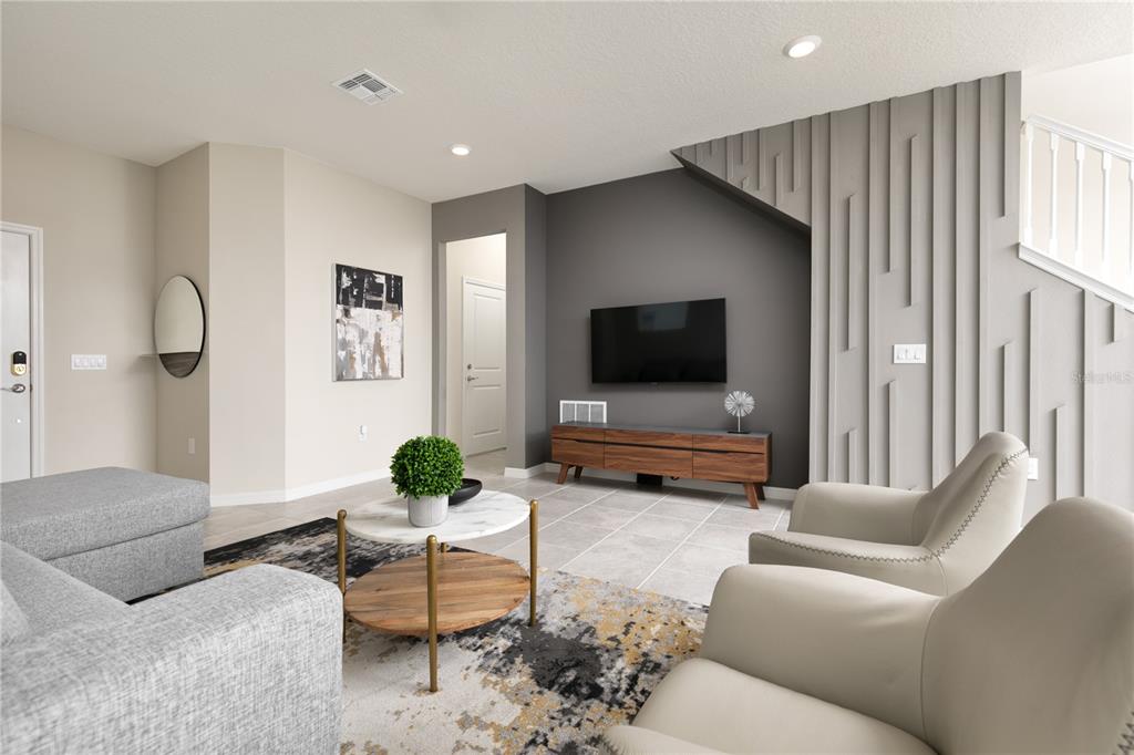 A modern living room features a gray accent wall, a television, and a textured wall feature — 7376 OAKMOSS LOOP, DAVENPORT, FL