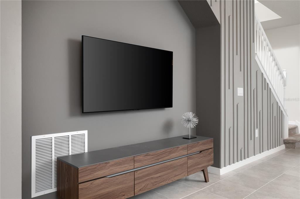 A wall-mounted television hangs above a wooden media console in a room with gray walls — 7376 OAKMOSS LOOP, DAVENPORT, FL
