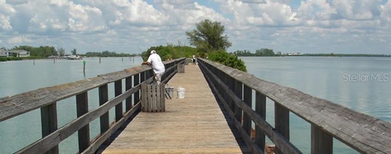 A wooden fishing pier extends over calm water under a cloudy blue sky — SABRINA TERRACE, NORTH PORT, FL