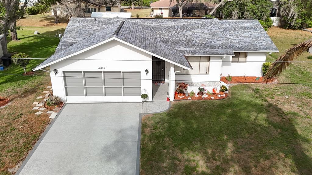 An aerial view of a white single-story house with a gray shingled roof and driveway — 5309 BAYONNE AVENUE, SPRING HILL, FL