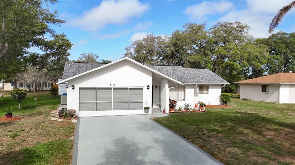 A single-story white house with a gray shingled roof and a concrete driveway — 5309 BAYONNE AVENUE, SPRING HILL, FL