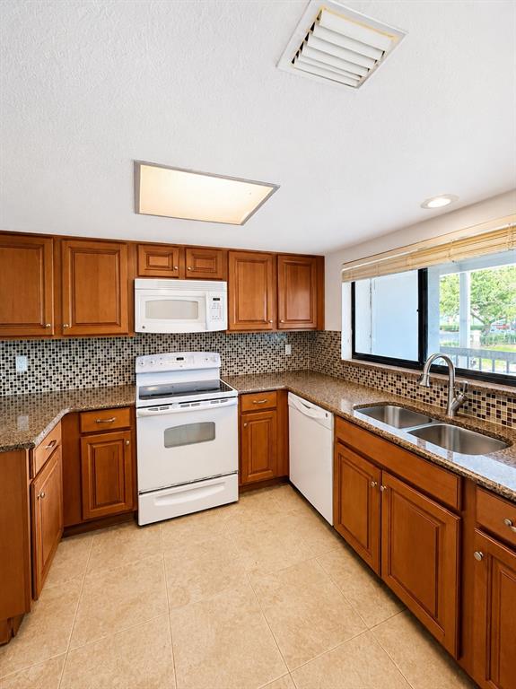 A kitchen features wood cabinets, a white stove, a double sink, and a tiled backsplash — 1054 LOTUS COVE COURT UNIT 633, ALTAMONTE SPRINGS, FL