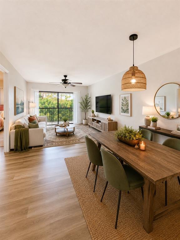 An open-concept living and dining area features wood-look flooring, a balcony, and neutral decor — 1054 LOTUS COVE COURT UNIT 633, ALTAMONTE SPRINGS, FL