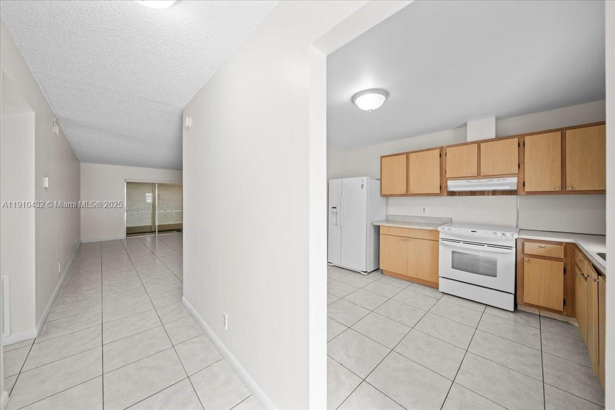 A kitchen with light wood cabinets and white appliances opens into a tiled living area — 508 Holyoke Ln # A, Lake Worth FL 33467, LAKE WORTH, FL