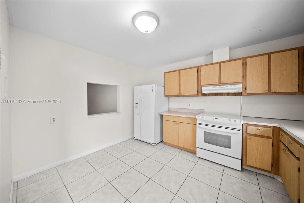 A kitchen features light wood cabinets, white appliances, and light-colored tile flooring — 508 Holyoke Ln # A, Lake Worth FL 33467, LAKE WORTH, FL