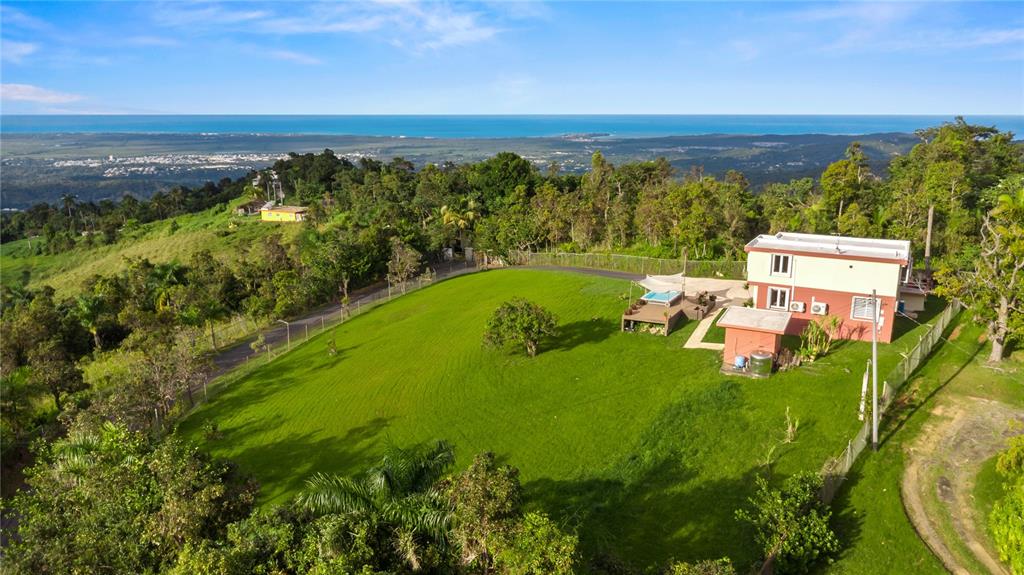 An aerial view shows a two-story house with a pool on a large grassy lot — Carr. 960 Km. 17.6 BO.GUZMAN ARRIBA, RIO GRANDE, PR