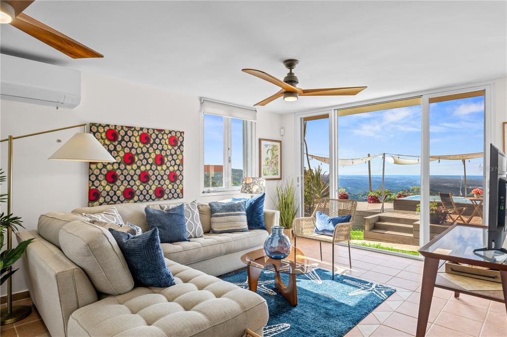 A living room features a beige sectional, blue accents, and sliding doors opening to a deck — Carr. 960 Km. 17.6 BO.GUZMAN ARRIBA, RIO GRANDE, PR
