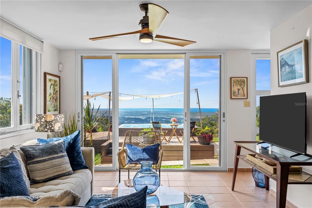 A living room with a ceiling fan, sliding glass doors, and a view of a pool — Carr. 960 Km. 17.6 BO.GUZMAN ARRIBA, RIO GRANDE, PR