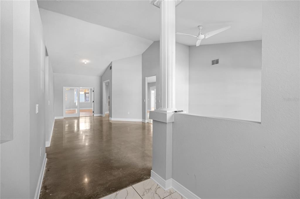 An interior view shows a room with polished concrete floors, a white column, and vaulted ceilings — 3616 CYPRESS MEADOWS ROAD, TAMPA, FL