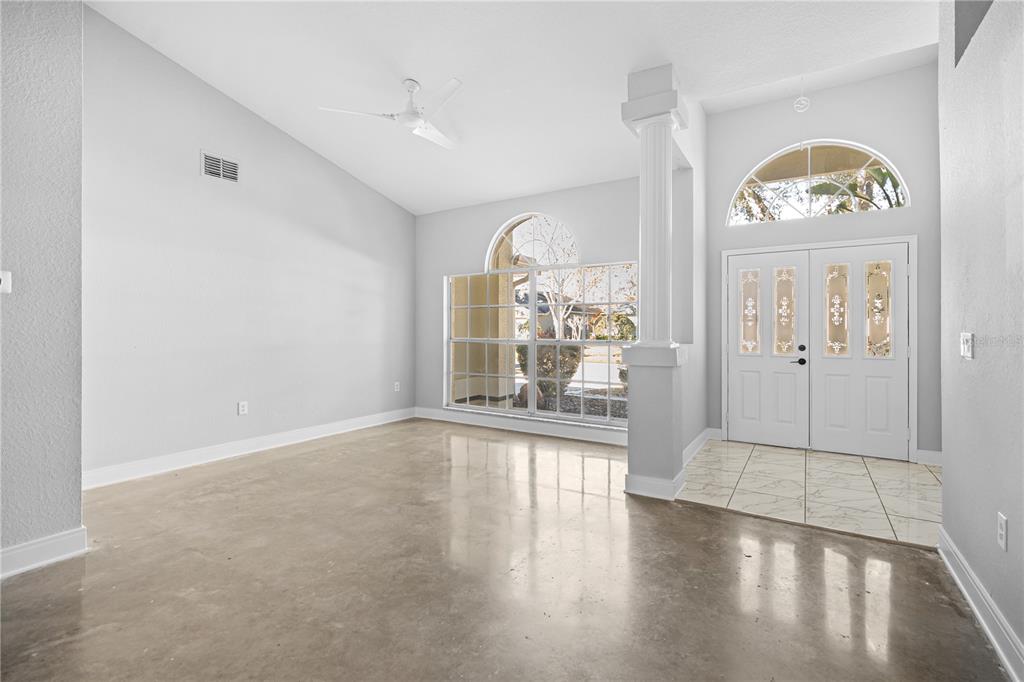 An empty room with light gray walls, polished concrete floors, a white column, and double doors — 3616 CYPRESS MEADOWS ROAD, TAMPA, FL