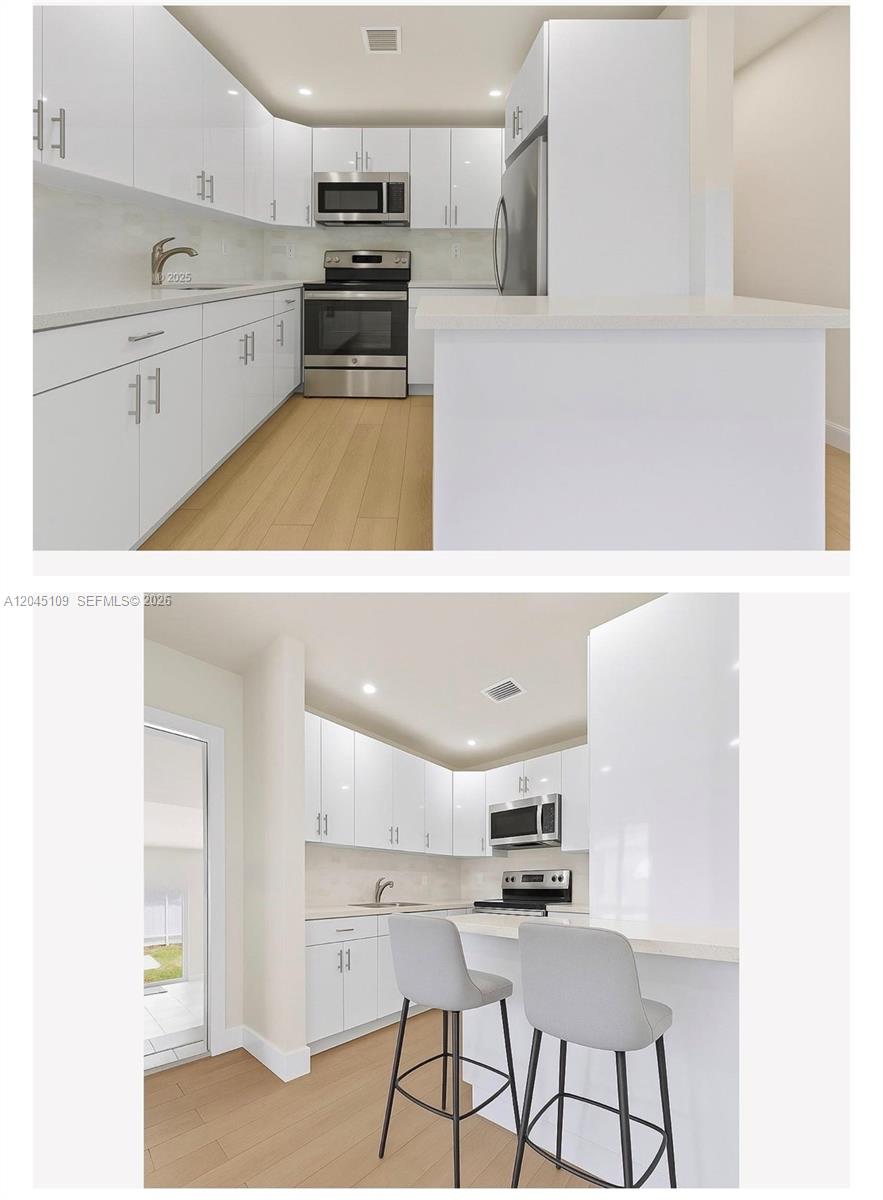A modern kitchen features white cabinets, stainless steel appliances, and a breakfast bar with stools — 3455 E 1st Ct # 3455, Hialeah FL 33013, HIALEAH, FL