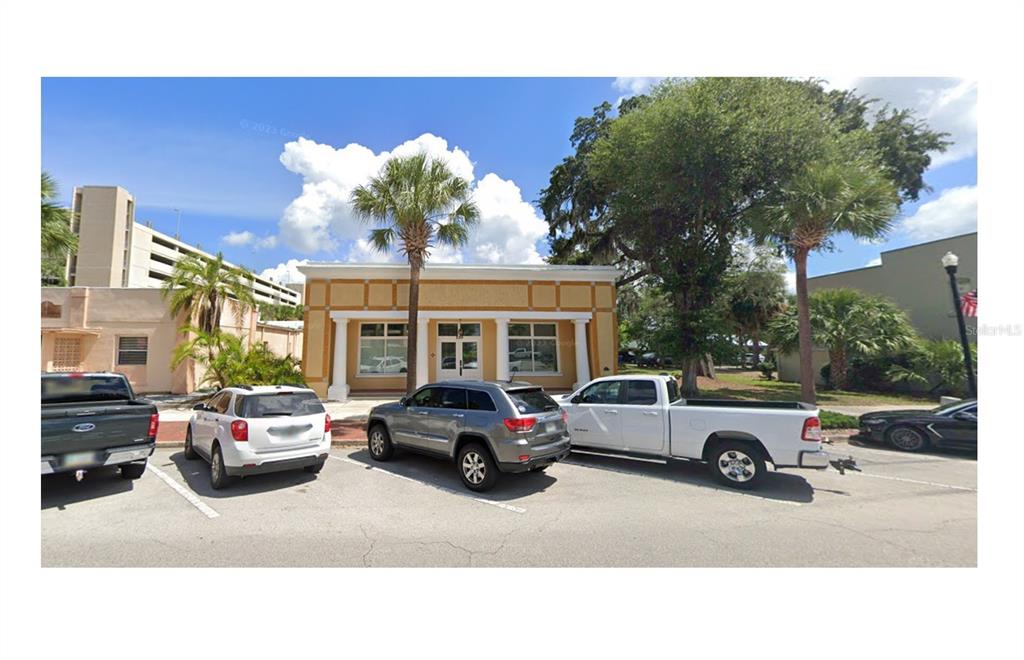 A single-story commercial building with a tan facade and columns stands behind a parking lot — 220 W MAIN STREET, TAVARES, FL