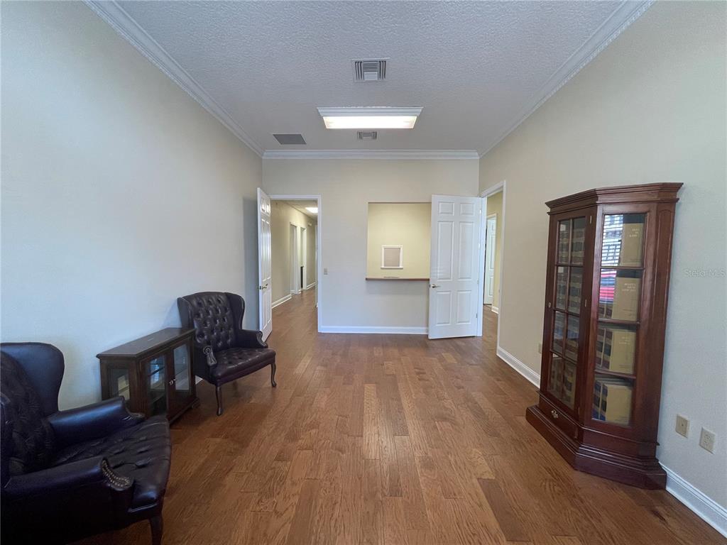A room with hardwood floors, two leather armchairs, a wooden bookcase, and open doorways — 220 W MAIN STREET, TAVARES, FL