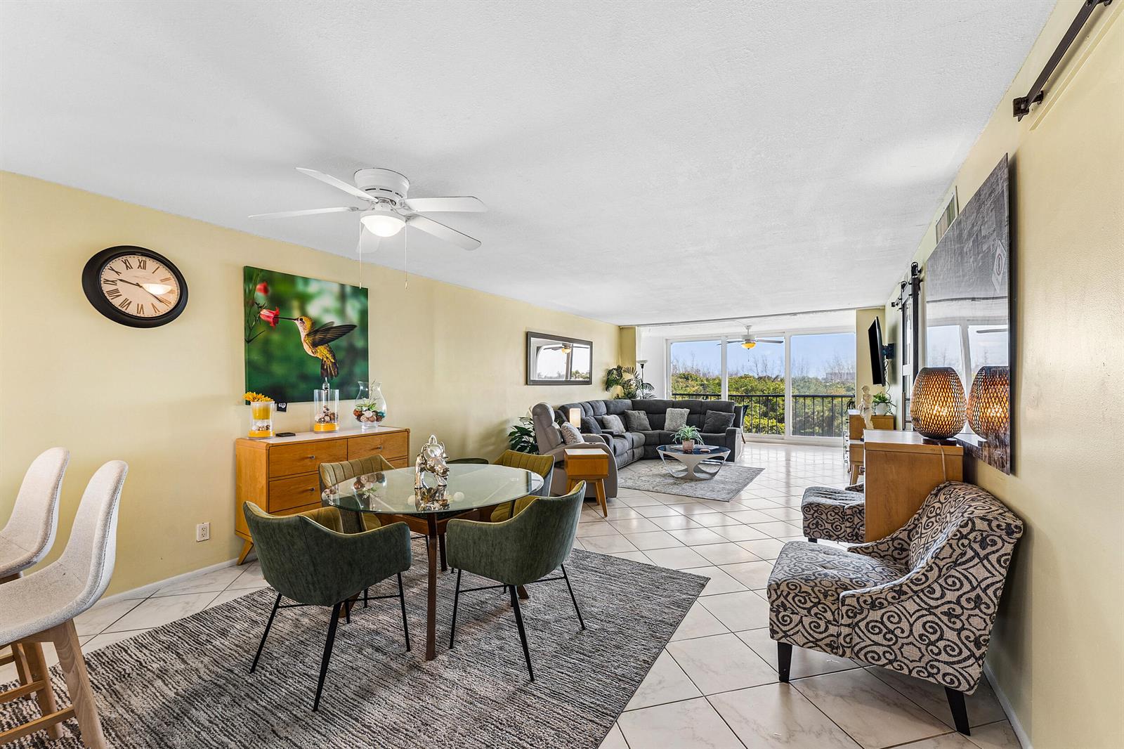 An open-concept living and dining area features tile floors, a glass dining table, and balcony — 1631 Riverview Road # 505, Deerfield Beach FL 33441, DEERFIELD BEACH, FL