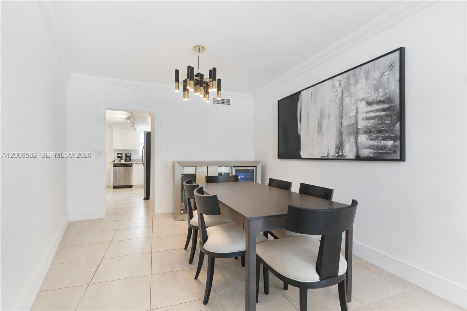 A dining room features a dark wood table, upholstered chairs, and a modern chandelier — 1142 99th St # 24, Bay Harbor Islands FL 33154, BAY HARBOR ISLANDS, FL