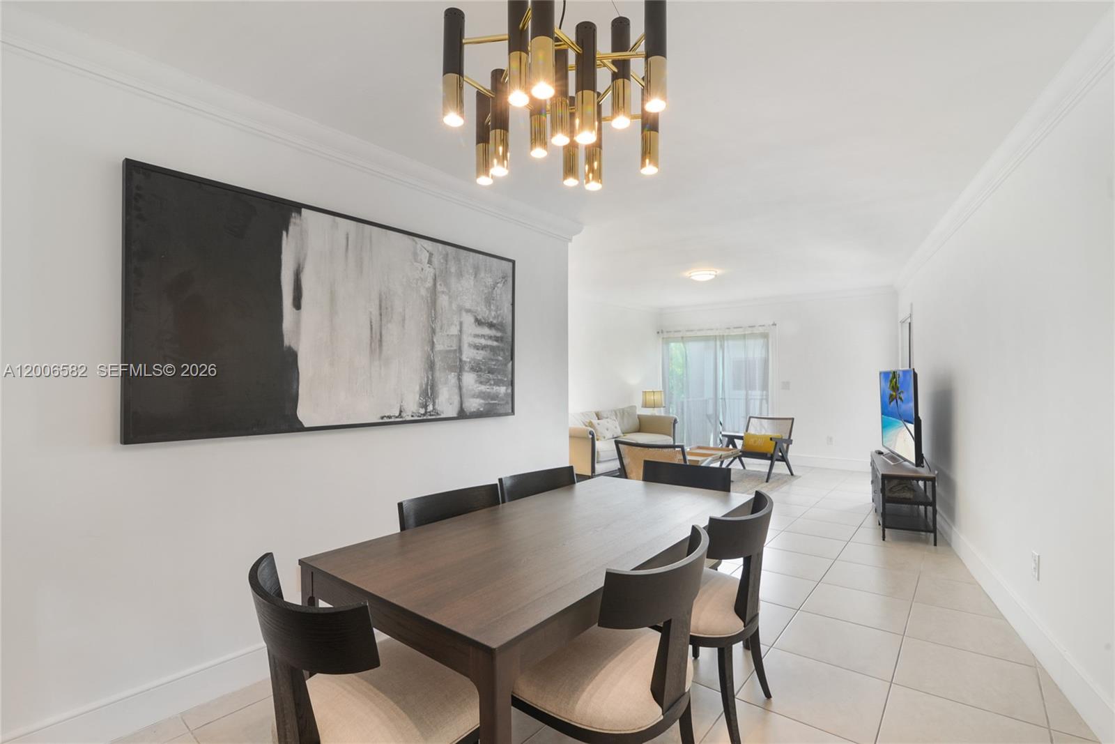 A dining area with a dark wood table and chandelier opens into a living room — 1142 99th St # 24, Bay Harbor Islands FL 33154, BAY HARBOR ISLANDS, FL