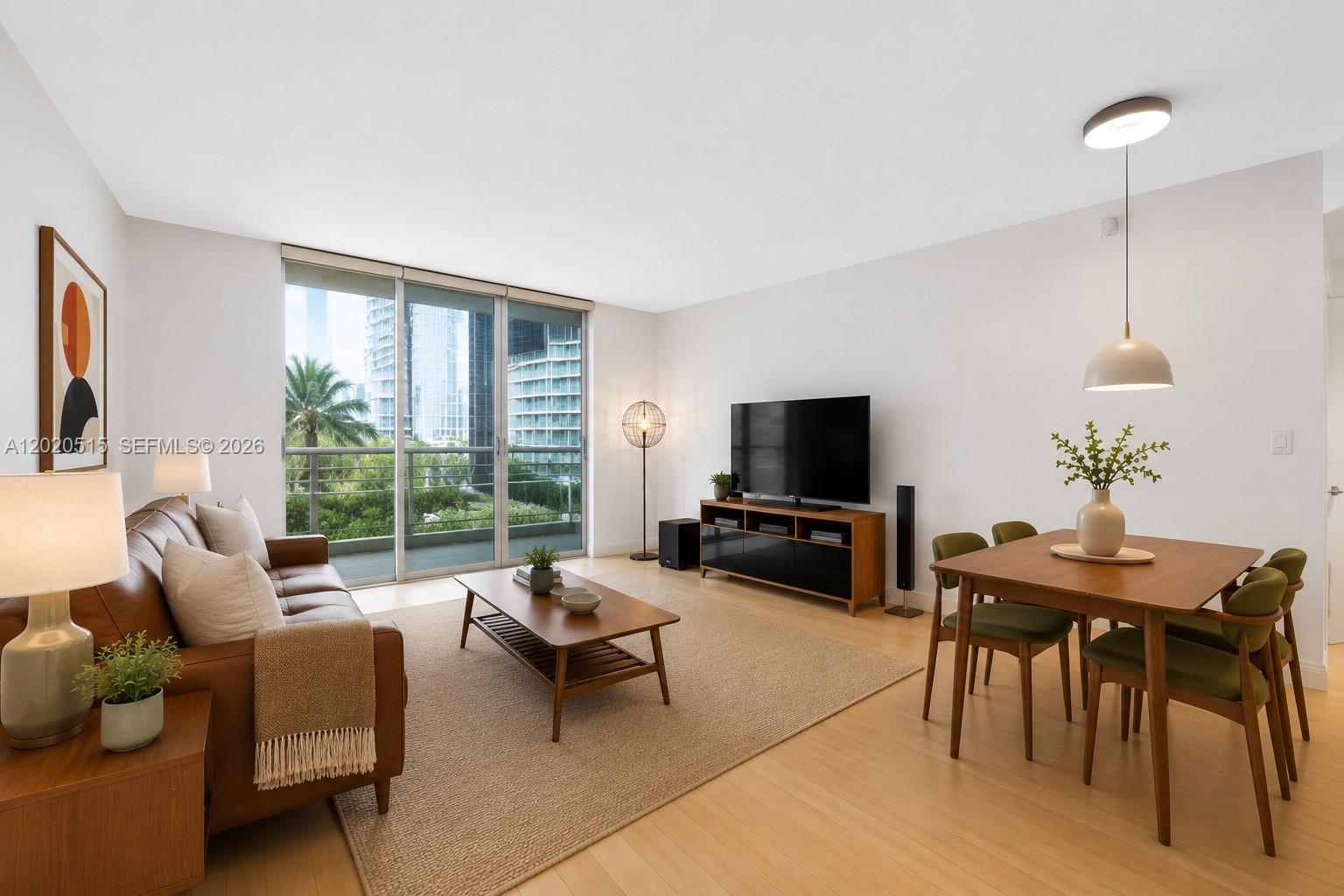 A living and dining area features a leather sofa, wood furniture, and a balcony view — 901 Brickell Key Blvd # 609, Miami FL 33131, MIAMI, FL