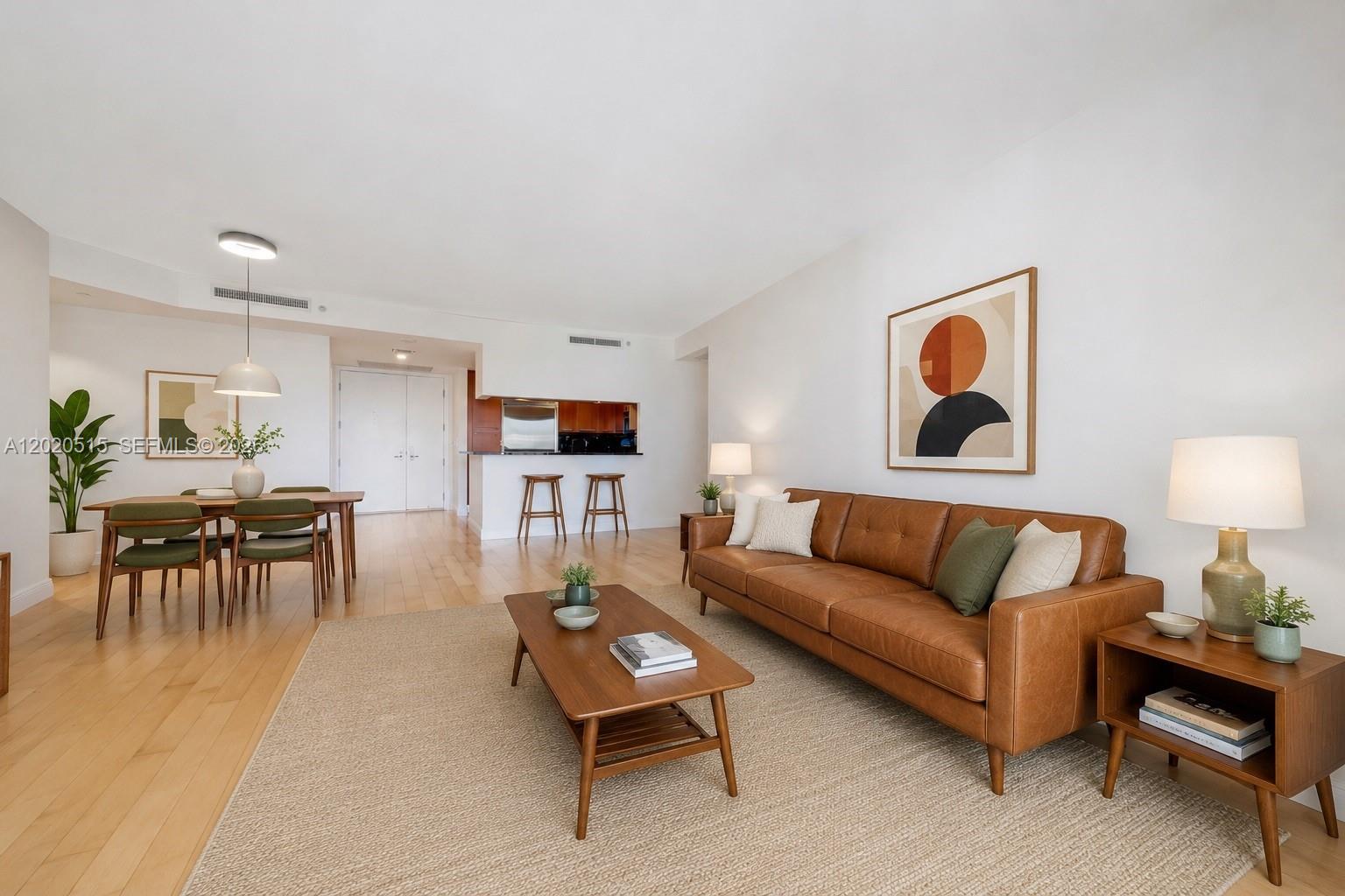 A living and dining area features a leather sofa, wooden furniture, and hardwood floors — 901 Brickell Key Blvd # 609, Miami FL 33131, MIAMI, FL