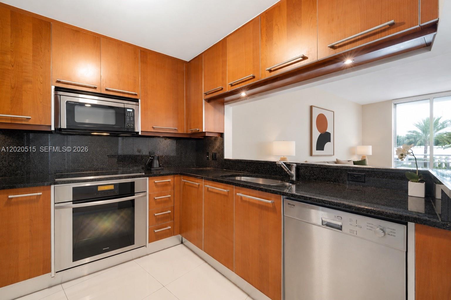 A kitchen with wood cabinets, stainless steel appliances, and black granite countertops — 901 Brickell Key Blvd # 609, Miami FL 33131, MIAMI, FL