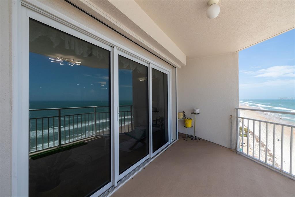 A balcony with a sliding glass door overlooks the ocean and a sandy beach — 2967 S ATLANTIC AVENUE UNIT 1204, DAYTONA BEACH SHORES, FL