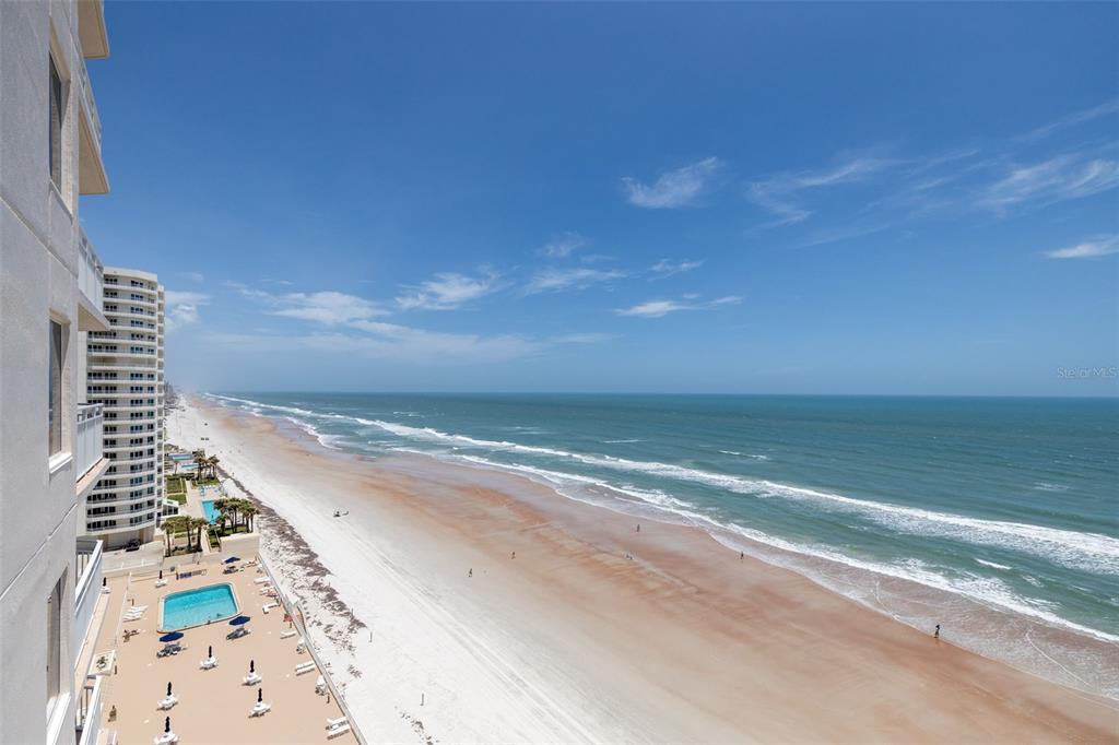 An elevated view of a sandy beach and ocean next to a high-rise building — 2967 S ATLANTIC AVENUE UNIT 1204, DAYTONA BEACH SHORES, FL
