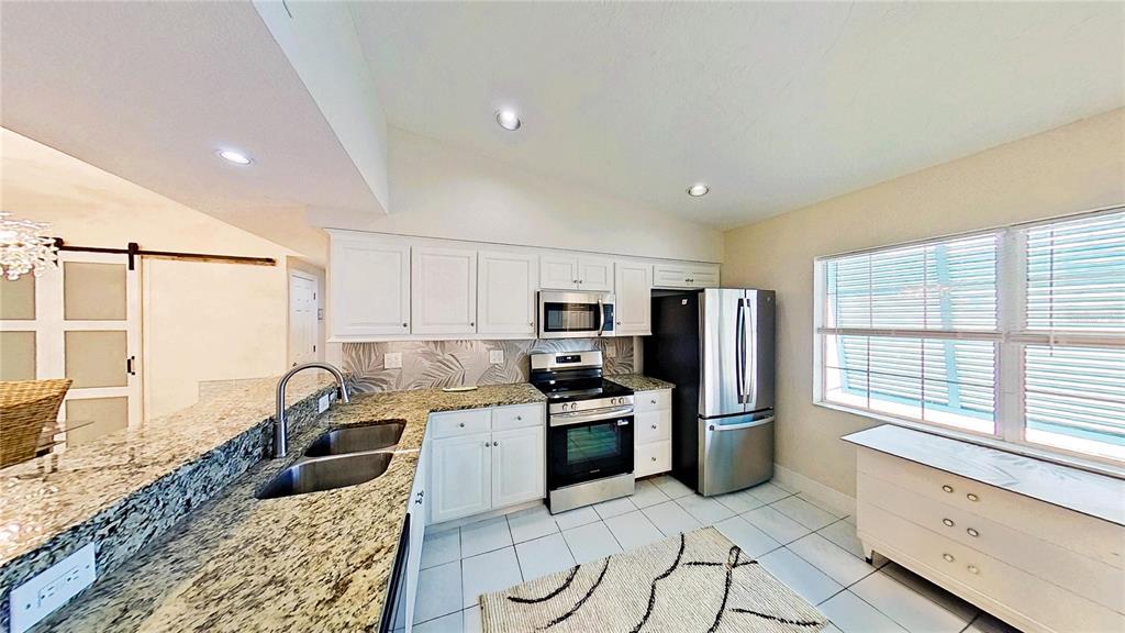 A kitchen features white cabinets, granite countertops, stainless steel appliances, and tile flooring — 3641 STOKES DRIVE, SARASOTA, FL