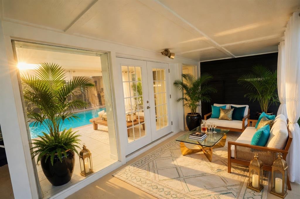 A covered patio features a seating area, a glass coffee table, and a view of a pool — 3641 STOKES DRIVE, SARASOTA, FL