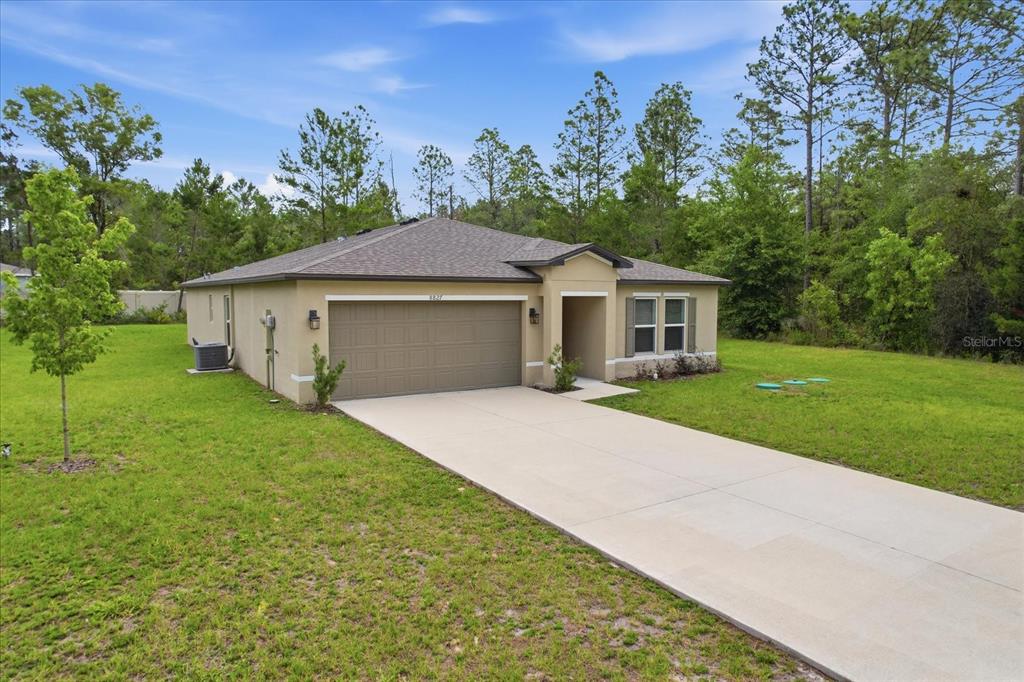 A single-story house with a tan stucco exterior, a two-car garage, and a concrete driveway — 8827 N VIENNA DRIVE, DUNNELLON, FL